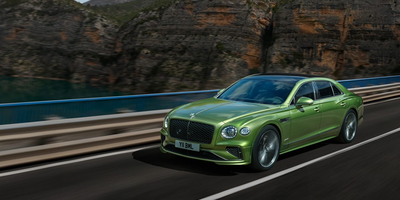Bentley Padova Bentley New Flying Spur Speed v8 hybrid sedan driving dynamically on a mountain road in Tourmaline Green paint