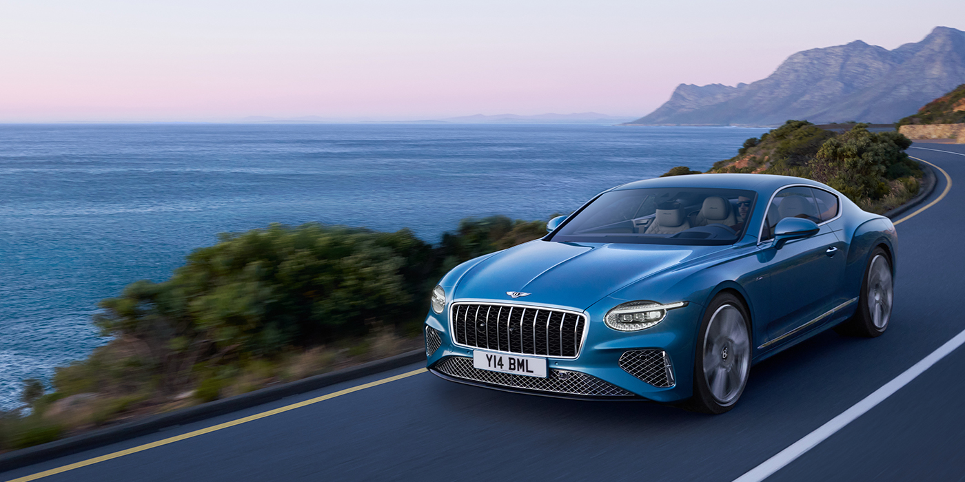 Bentley Padova New Bentley Continental GT Azure coupe in Light Windsor blue paint with 22 inch Azure wheels and chrome grill, driving dynamically by the sea