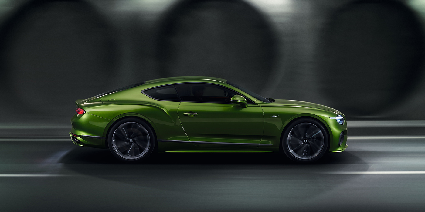 Bentley Padova Bentley Continental GT coupe in Tourmaline Green paint driving in profile on a dark road