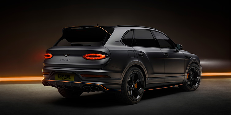 Bentley Padova Bentley Bentayga S Black Edition SUV rear three quarter in Anthracite Satin paint against a dark red and yellow background