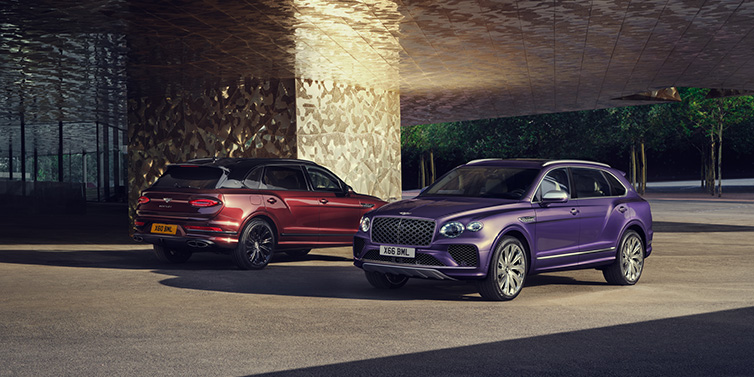 Bentley Padova A duo of Bentley Bentayga Extended Wheelbase Mulliner SUVs parked in a city environment, with Tanzanite Purple and Cricket Ball red exterior paint